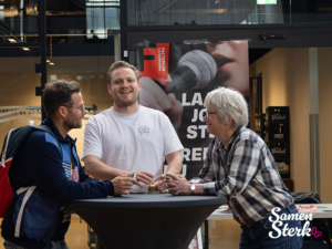 Drie deelnemers met elkaar in gesprek bij statafel